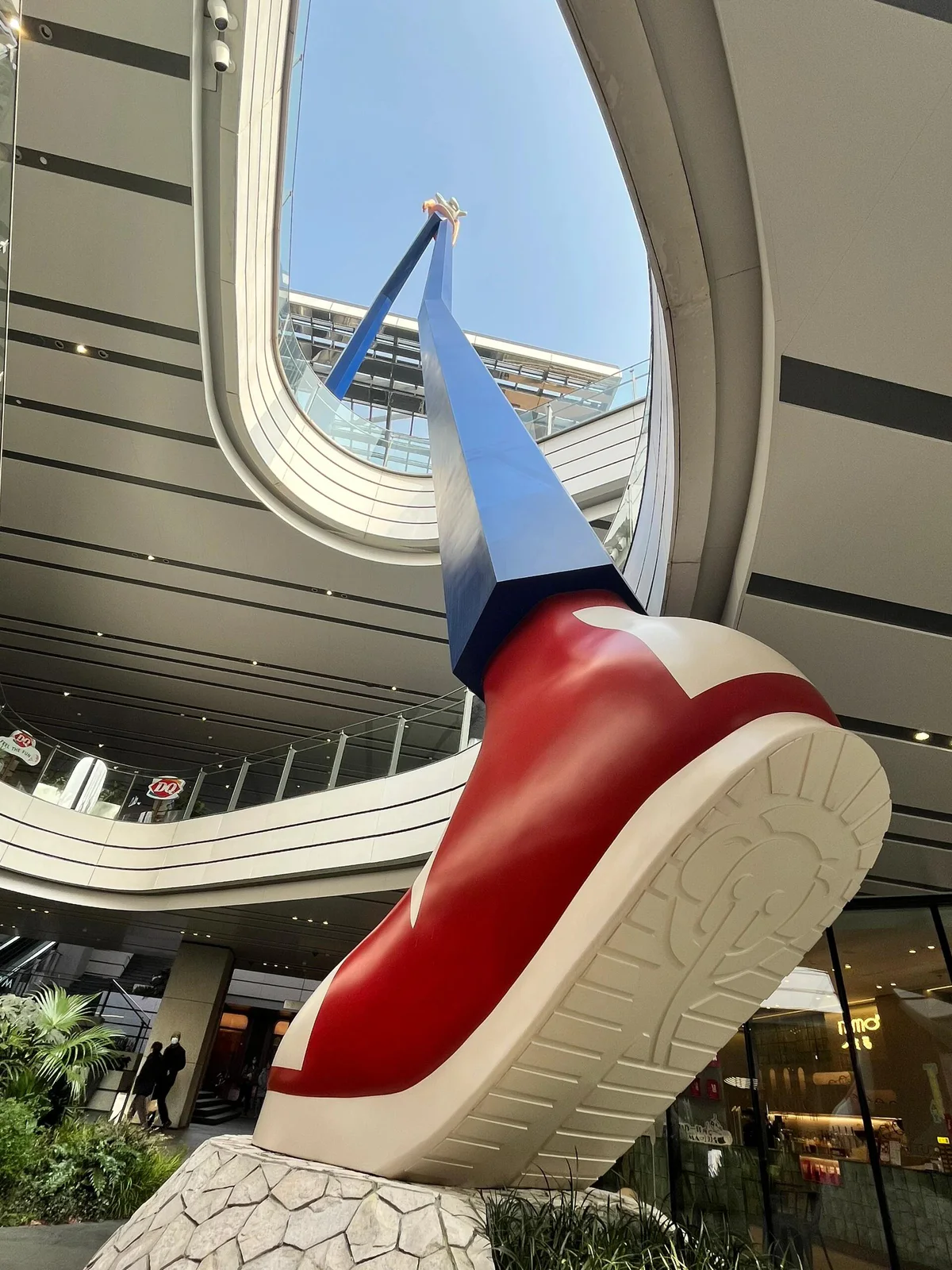 Oversized sculptural shoe form beside planting and lower-level guest circulation