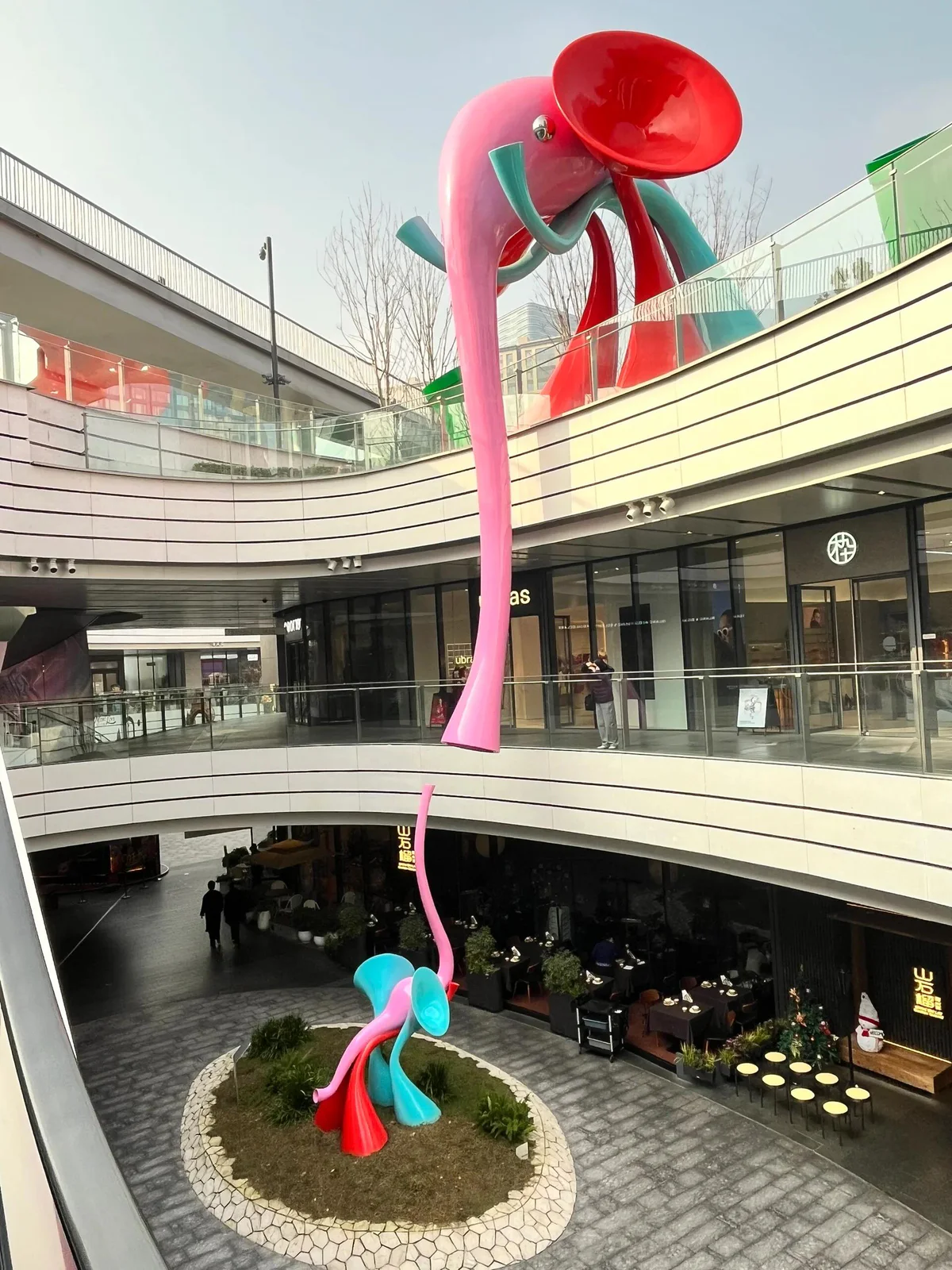Colourful large sculpture extending across several levels of a commercial atrium