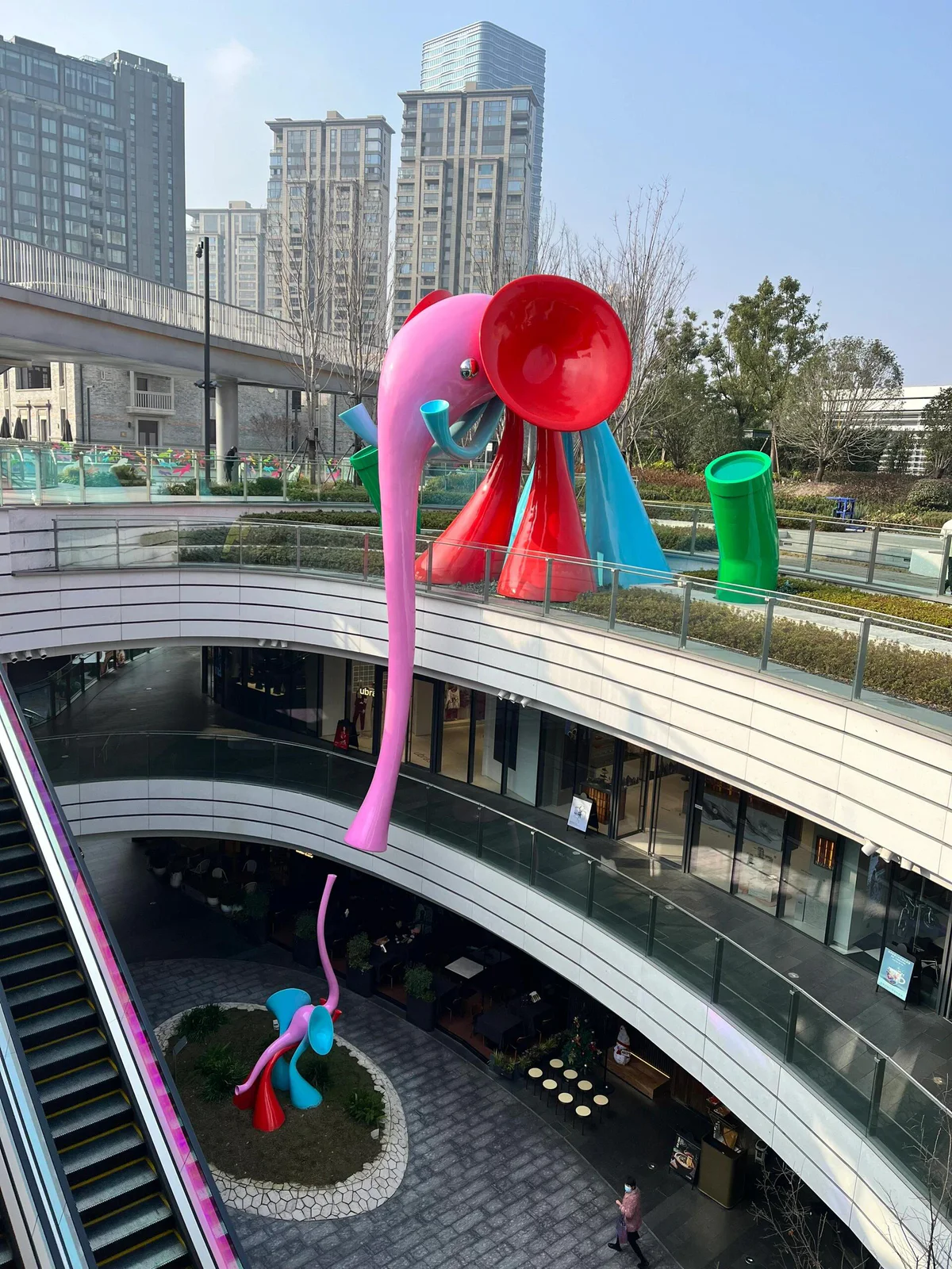 Commercial atrium sculpture seen beside an upper terrace and roof opening