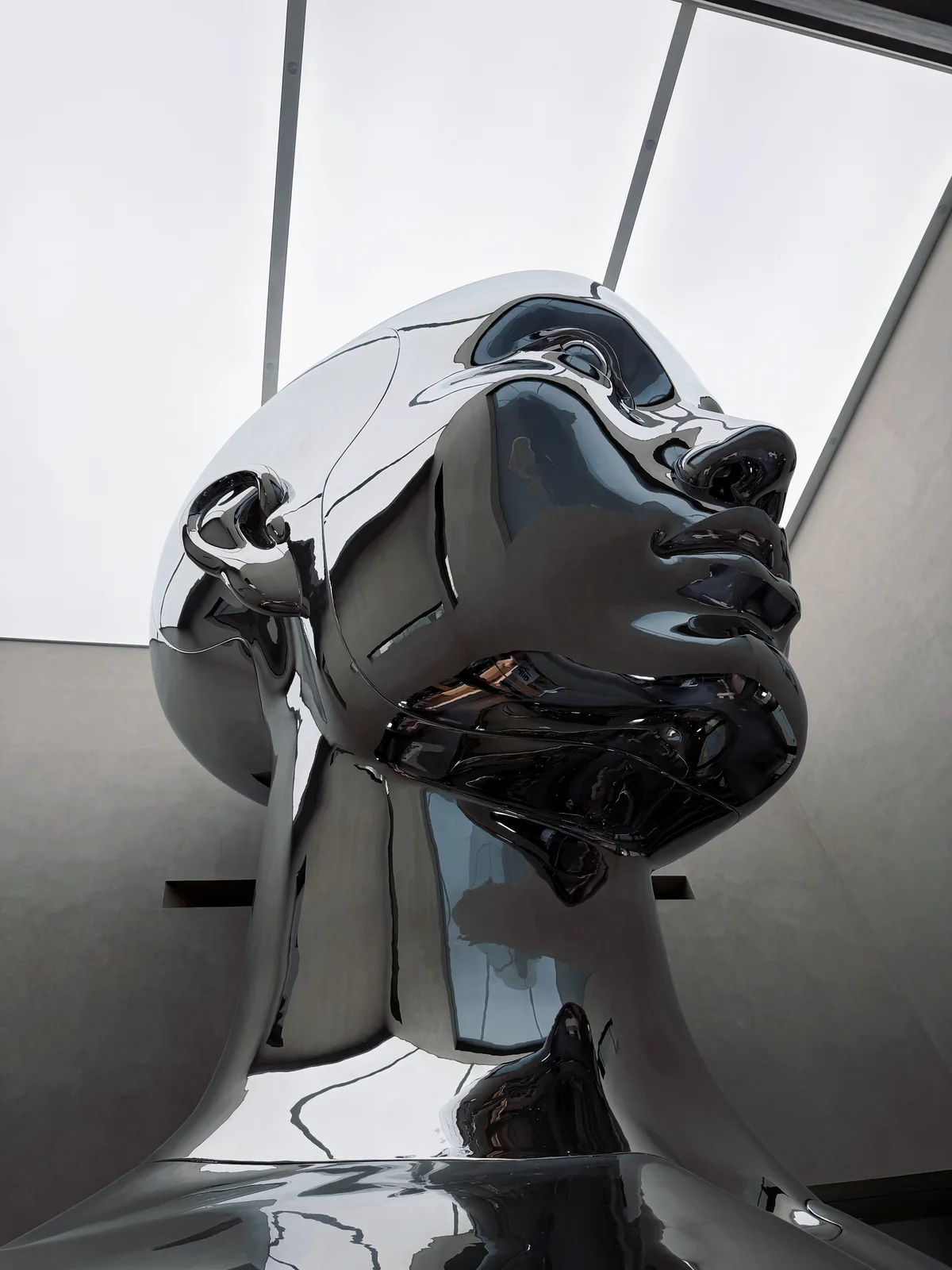 Close upward view of large mirror stainless steel atrium sculpture showing panels highlights and skylight relationship