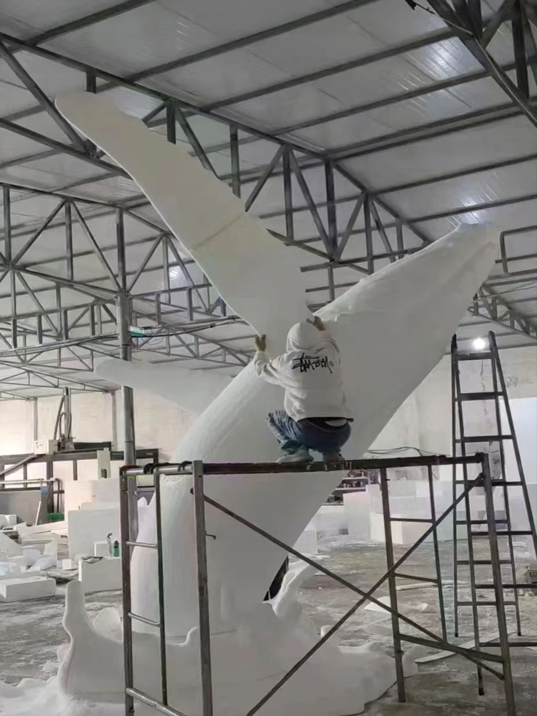 Large sculptural form under fabrication with scaffold access and temporary workshop support
