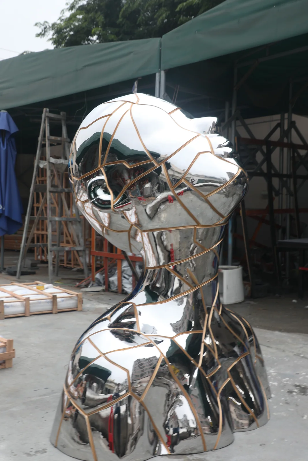 Workshop view of mirror polished stainless steel sculpture with bronze toned panel inlays
