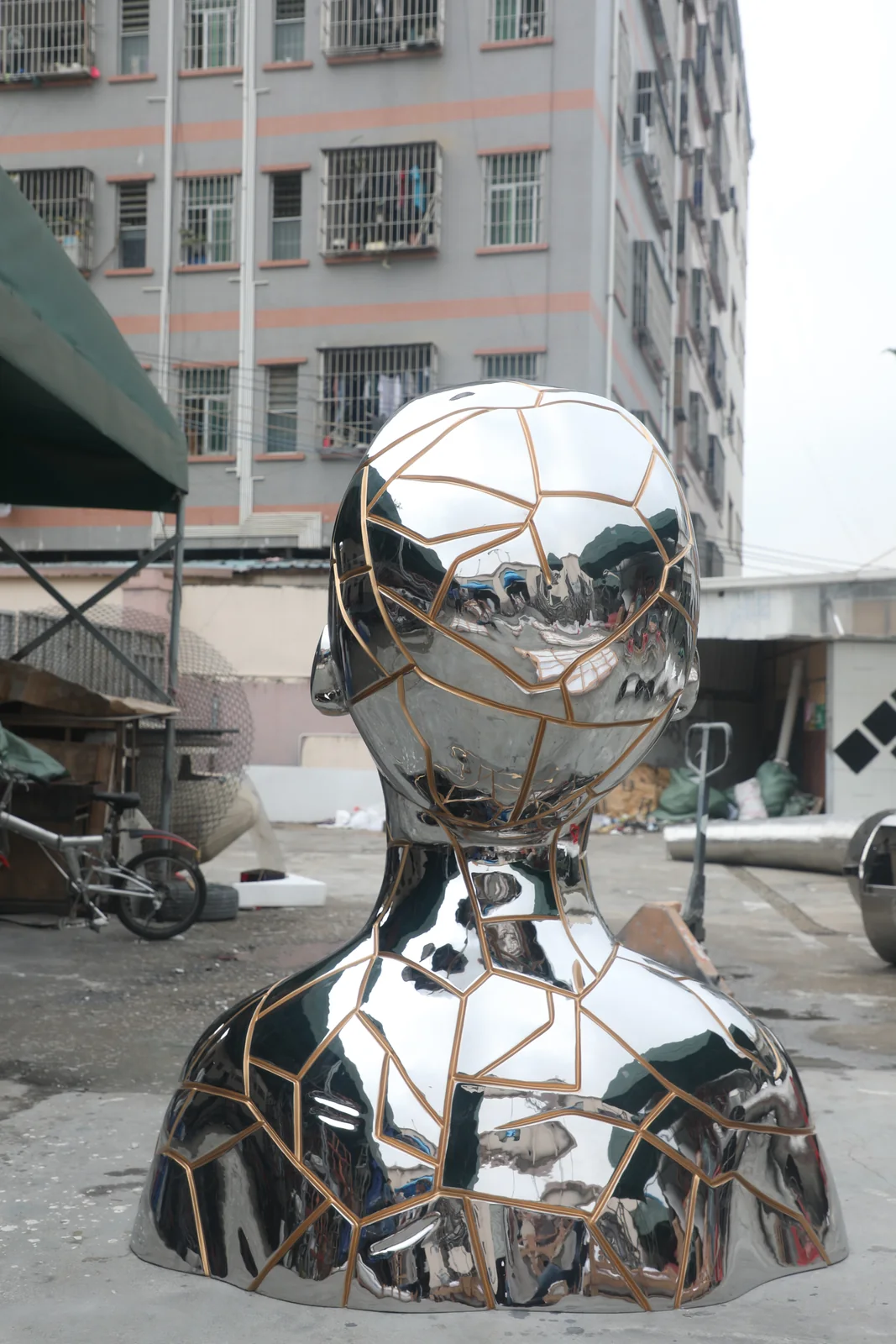 Rear workshop view of mirror polished stainless steel sculpture with bronze toned inset lines