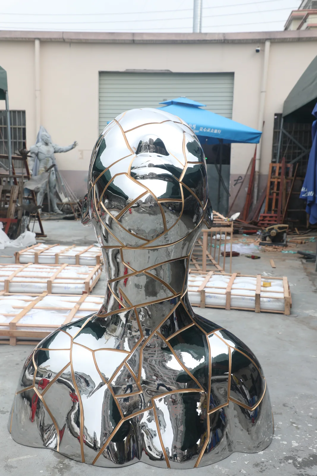Mirror polished stainless steel sculpture with bronze toned inset lines during workshop finish review